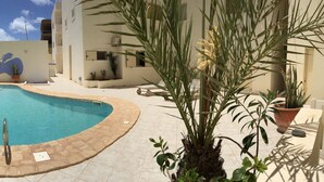 A swimming pool with a tiled deck, surrounded by potted plants and a building with a 'Sale Office' sign. - Boa Vista Holidays (Boa Vista)