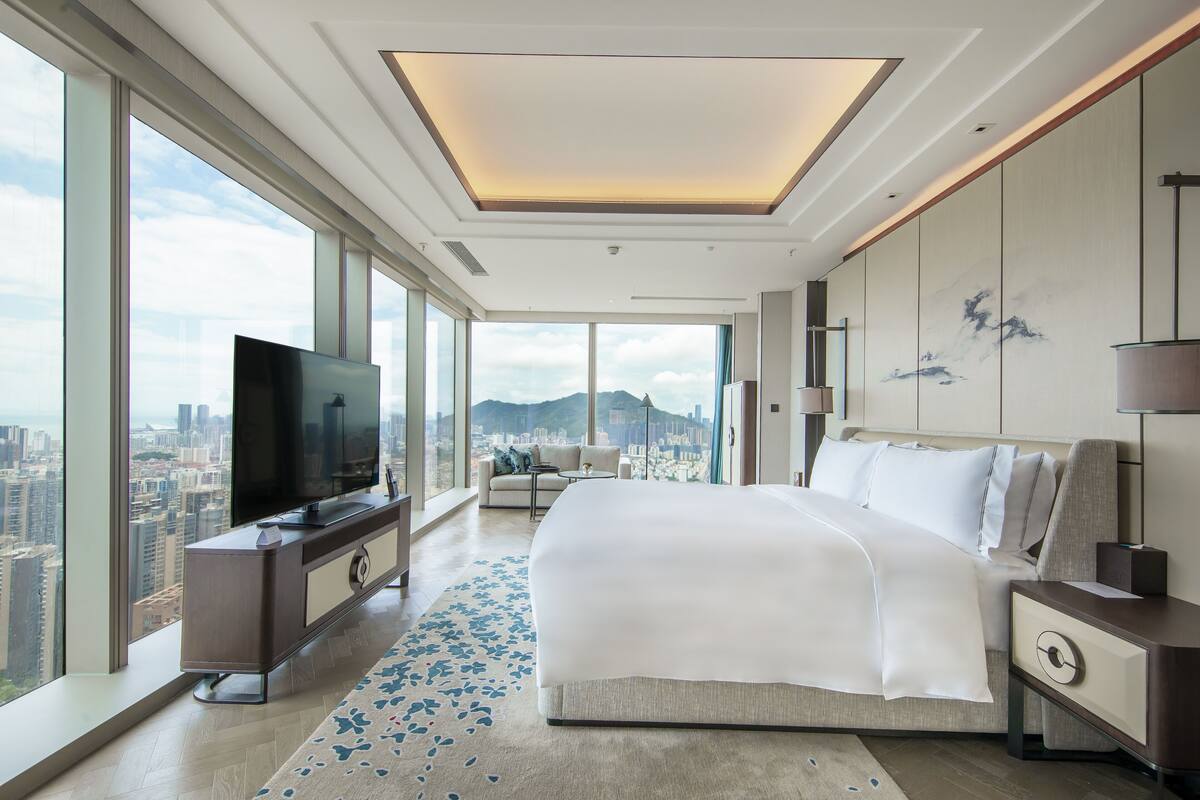 A modern hotel room with a large bed, a TV, and a city view.