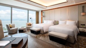 Habitación de hotel con dos camas, un escritorio, una silla y vista al mar.