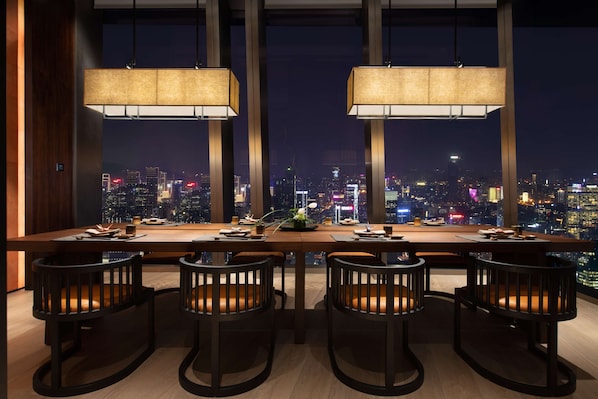 A modern dining area with a city view, featuring a long table with chairs and pendant lights. - Raffles Shenzhen (Shenzhen)
