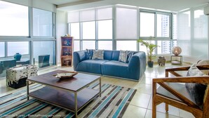 A spacious living room with a blue sofa, wooden coffee table, and a striped rug.