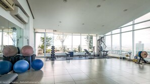 A spacious gym with exercise equipment, large windows, and a view of the city.