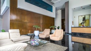 A modern lobby with leather sofas, a glass coffee table, and potted plants.
