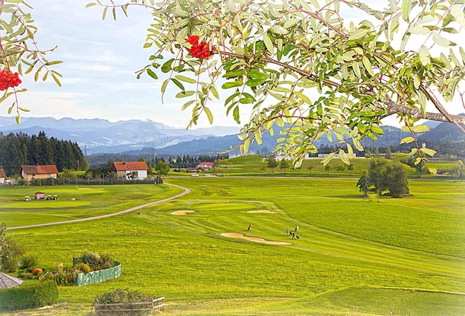 A golf course with a clear view of the fairway, sand bunkers, and a distant mountain range.