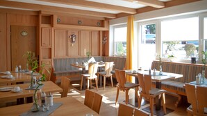 Un restaurante con mobiliario de madera, ventanas amplias y vistas al exterior.