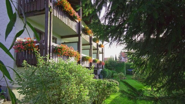 Un edificio de dos pisos con balcones decorados con macetas llenas de flores.