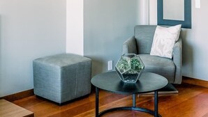 Un salón moderno con un sofá gris, una mesita redonda pequeña y un florero de vidrio hexagonal.