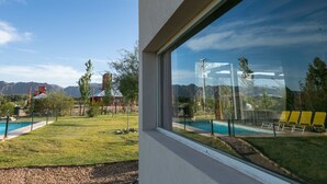 Zona de piscina con vistas despejadas a montañas al fondo, un área de descanso cubierta y una piscina cercada.