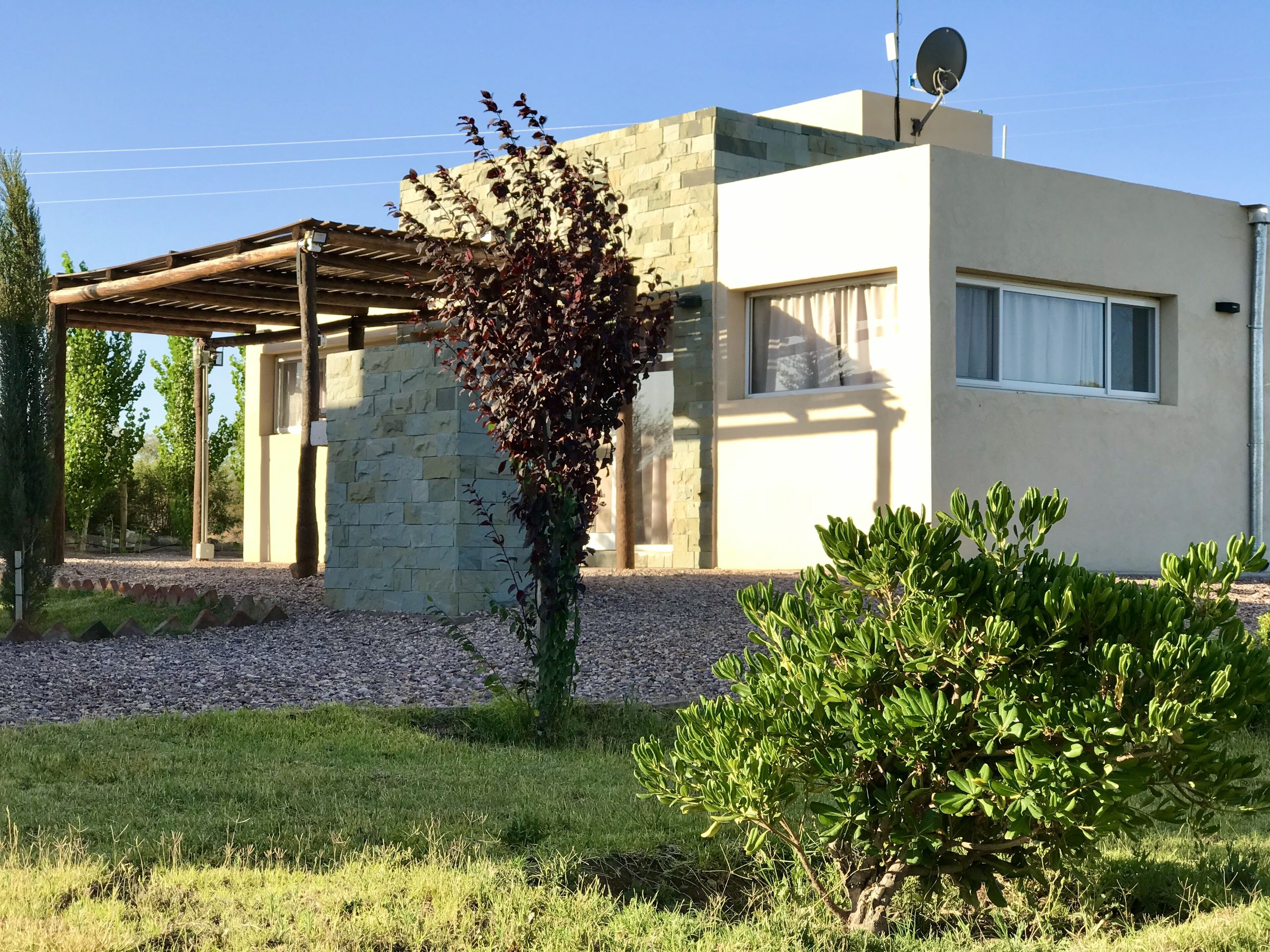 A modern building with a stone facade, a covered patio, and a well-maintained garden.