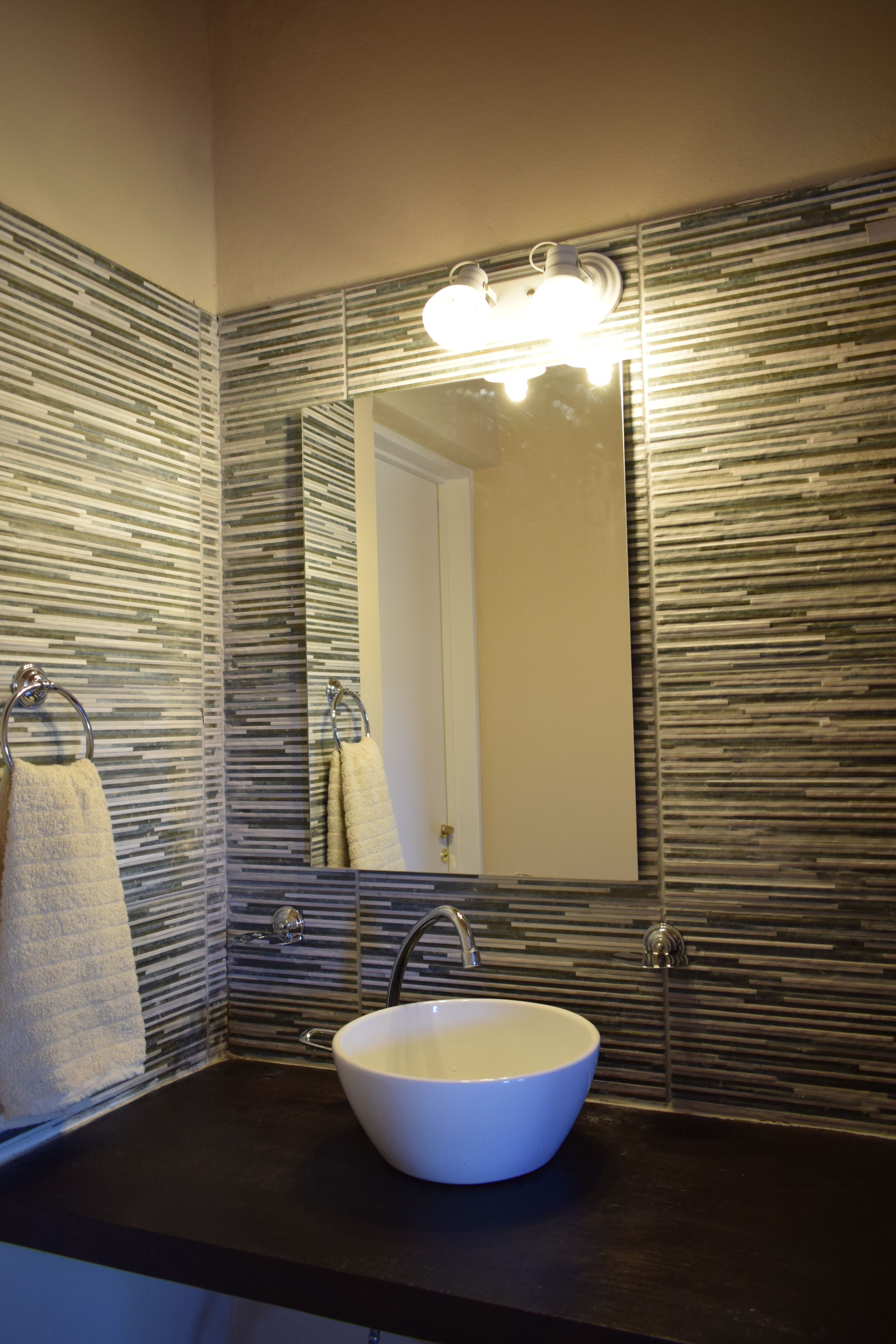 A bathroom with a large mirror, a white sink, and a towel rack.