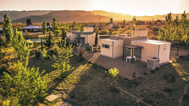 Una zona residencial moderna con varias casas, rodeada de árboles y colinas al fondo.