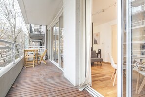 A modern apartment with a wooden deck, large sliding glass doors, and a view of the city.
