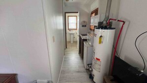 A narrow hallway with a white radiator, a water heater, and a black television on a stand.