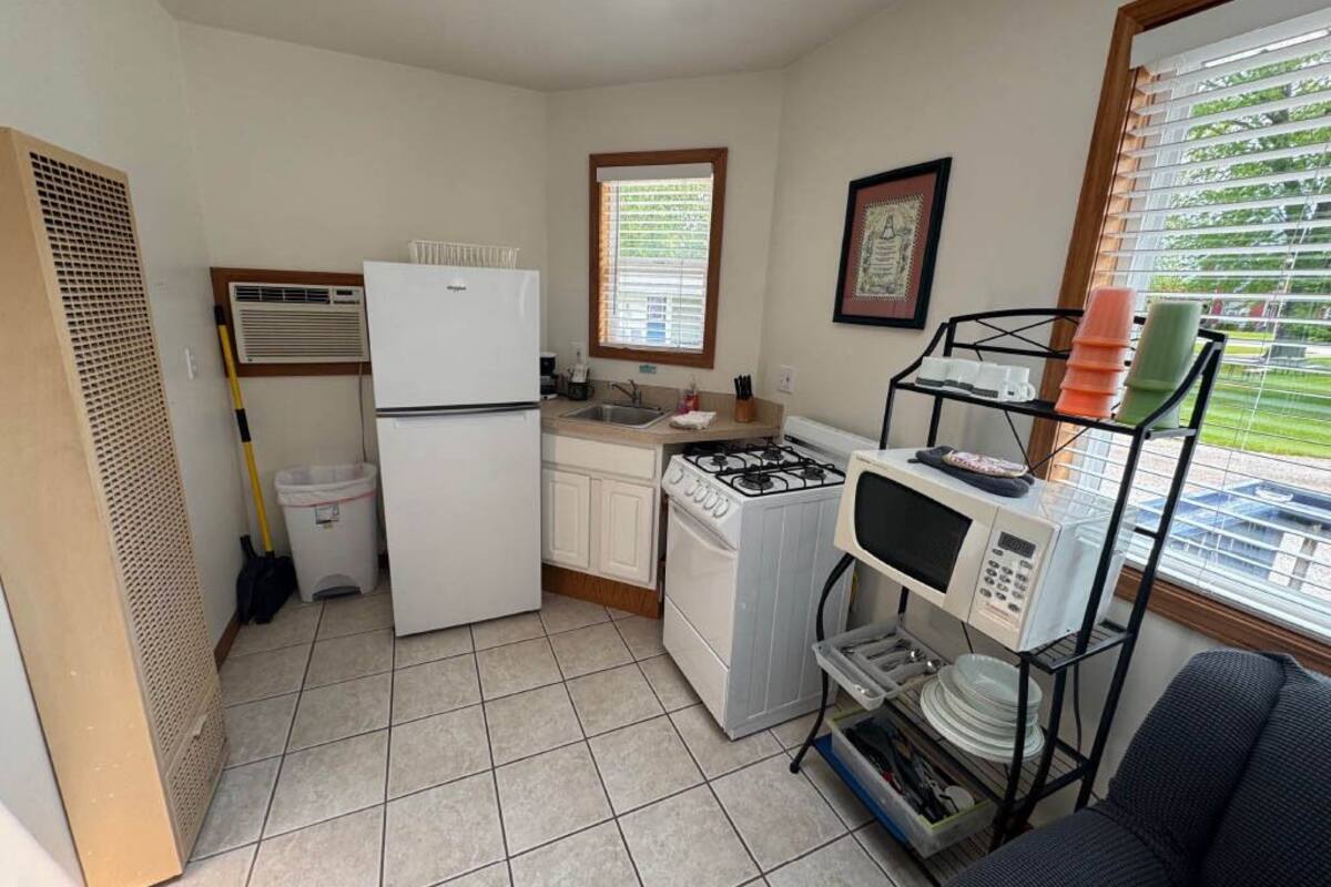 A compact kitchen with a refrigerator, stove, microwave, and a sink.