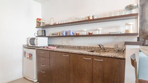 Eine Küche mit Holdelementen, einer Granit Arbeitsplatte, einer Mikrowelle, einer Kaffeemaschine und Regalen mit Gläsern und Dekoration.
