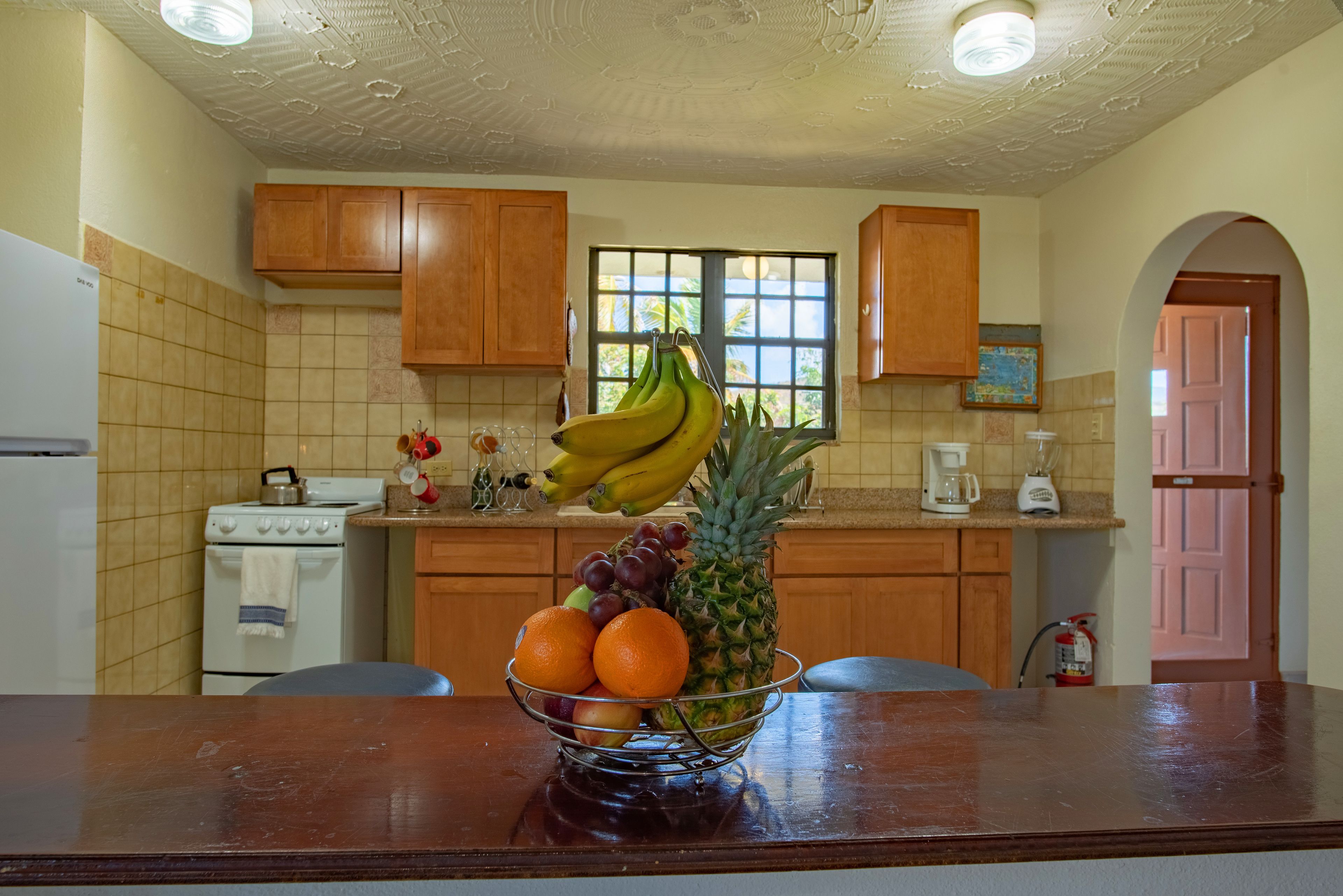 A kitchen with wooden cabinets, a stove, and a fruit bowl on the counter.
