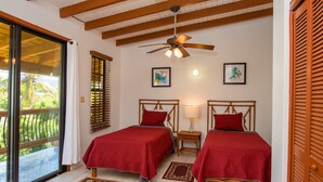 A room with two beds, a ceiling fan, and a sliding glass door leading to a balcony. - Bayview Vacation Apartments (Virgin Gorda)