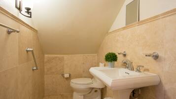 A bathroom with a toilet, sink, and shower area.