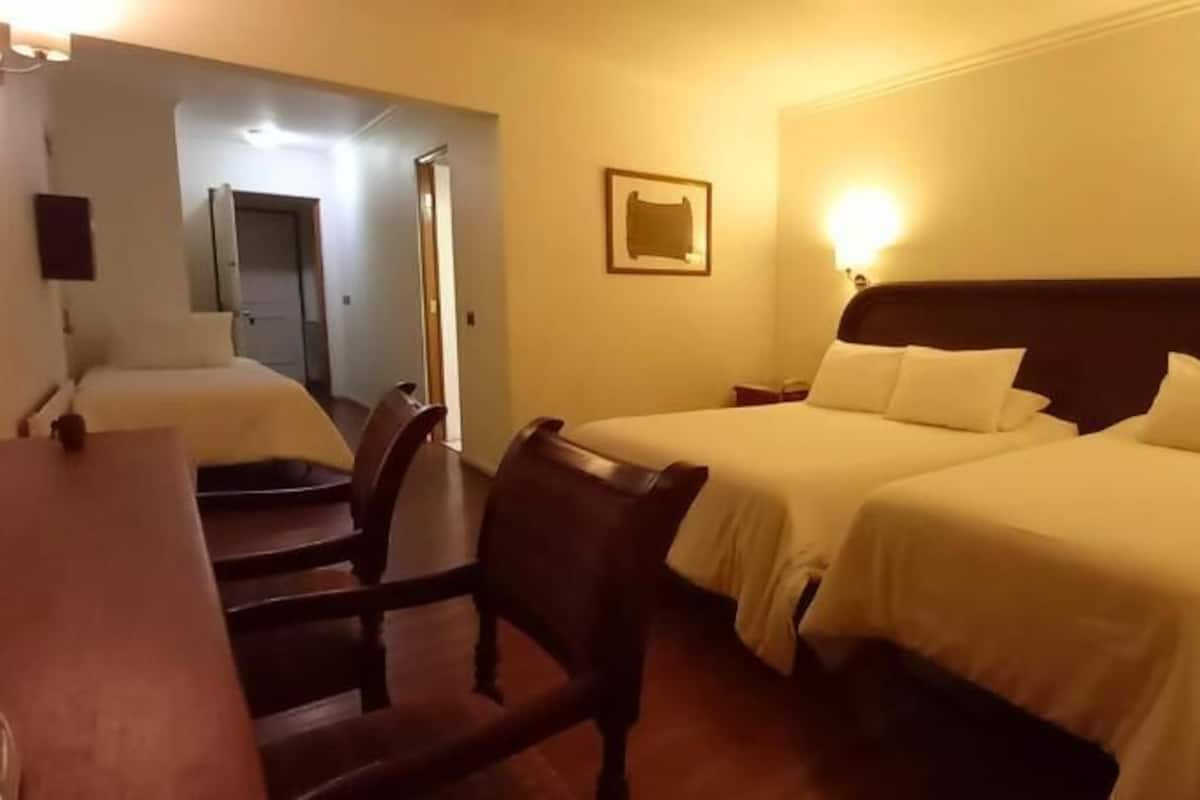 Habitación de hotel con dos camas, un escritorio y una silla.