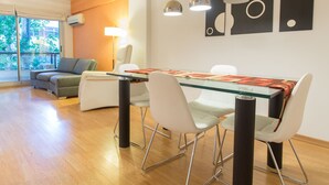 Een moderne eetruimte met een glazen tafel, witte stoelen en hanglampen.