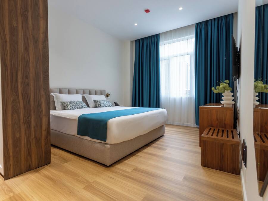 Un dormitorio moderno con una cama grande, suelo de madera, una mesita de noche y un espejo.