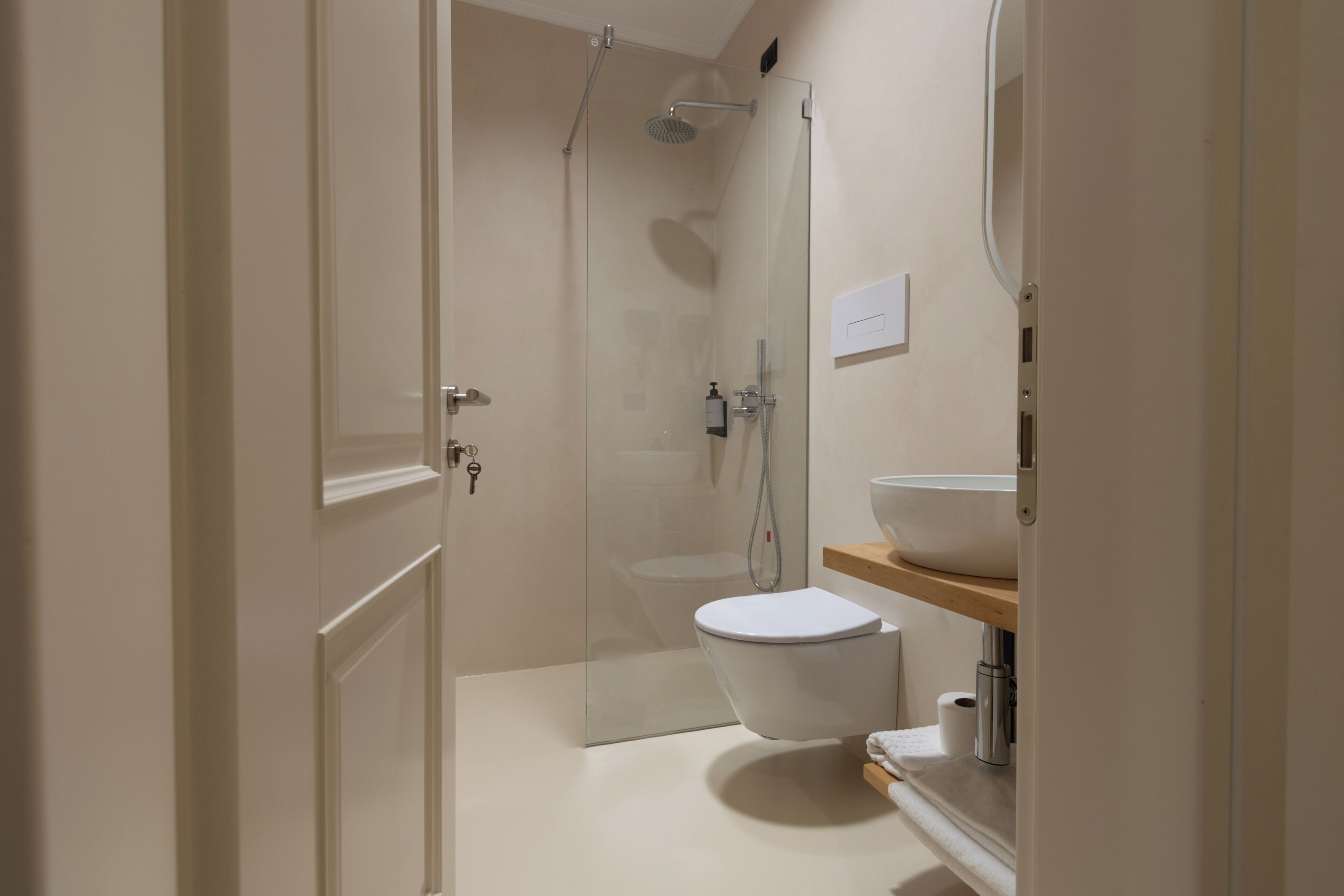 A modern bathroom with a glass-enclosed shower, a white toilet, and a wooden vanity with a sink.