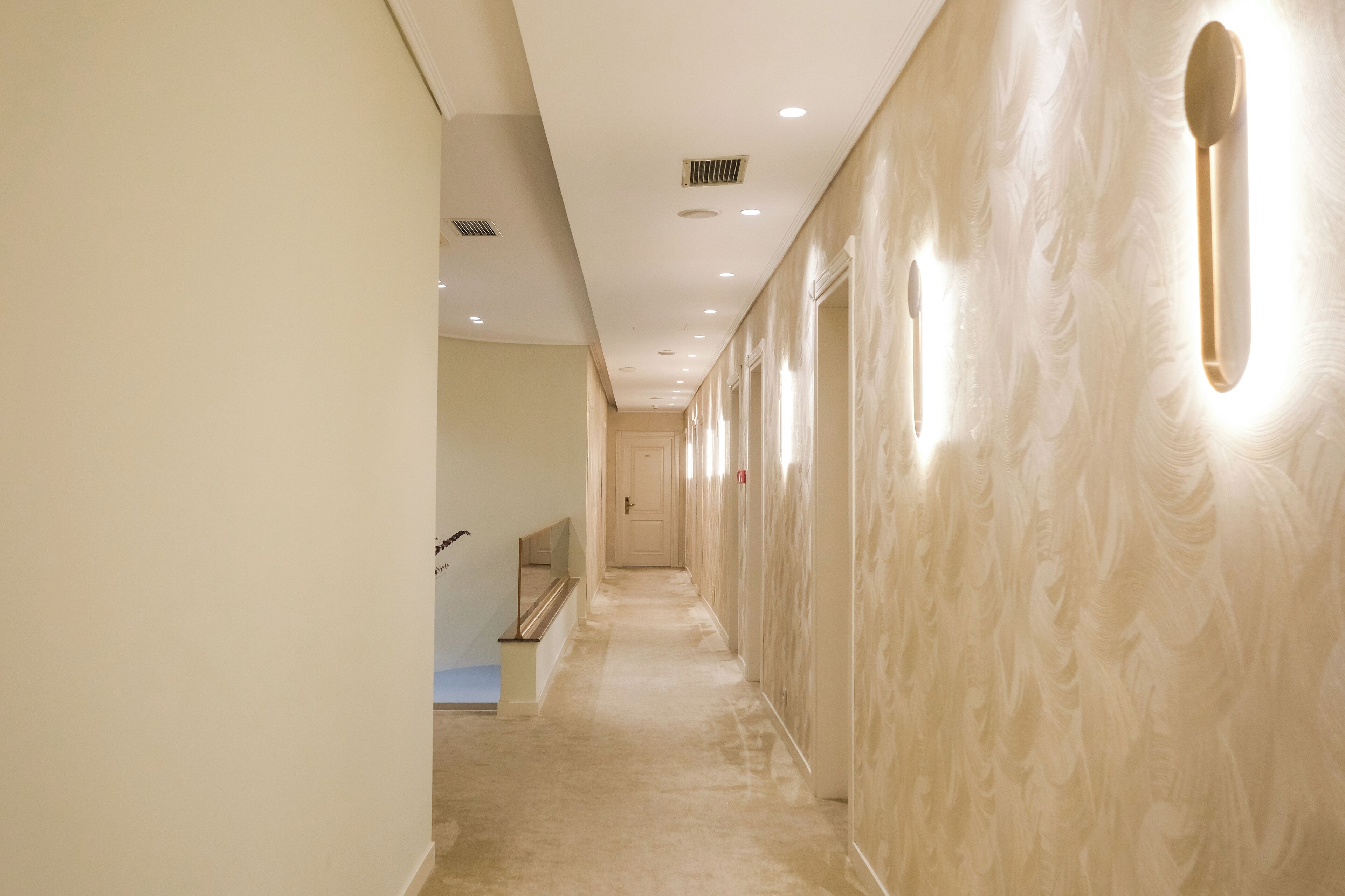 A hallway with a marble-like wall and recessed lighting.