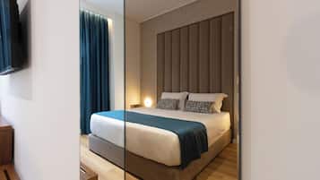 Ein modernes Hotelzimmer mit einem großen Bett, einem flachbildfernseher an der Wand und einer hölzernen Sitzbank.
