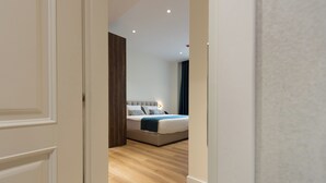 Quarto com cama, porta de madeira e parede em tom claro.