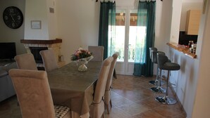 Ein Essbereich mit Tisch, Stühlen, einem Blumenstrauß und einer Küchenzeile mit Sitzgelegenheiten.