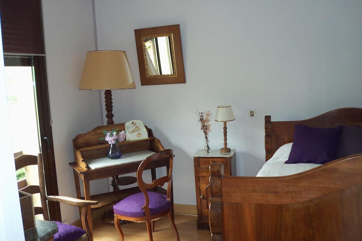 Ein Schlafzimmer mit einem hölzernen Bett, einem Schreibtisch, einem Stuhl und zwei Nachttischen mit Lampen.