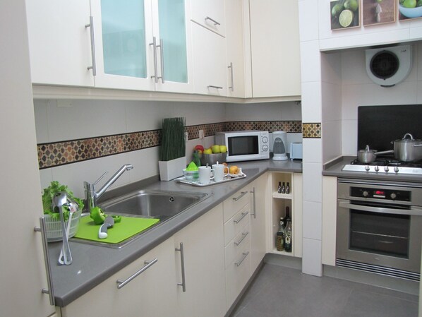 A modern kitchen with a stainless steel sink, a microwave, a toaster, and a stove.