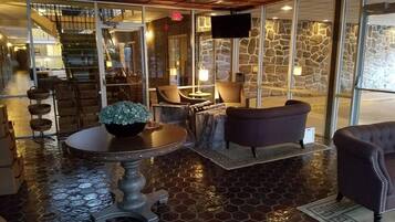 A lobby with a stone wall, a round table with a plant, and a sofa.