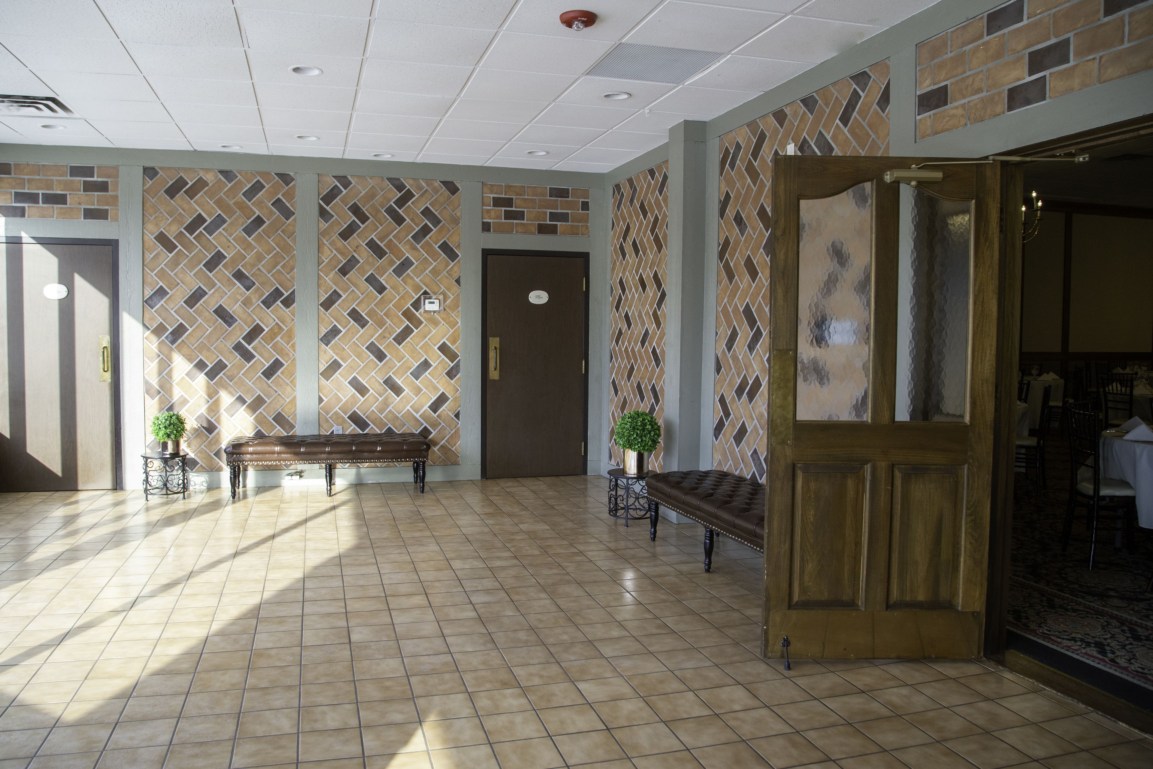 Un vestíbulo con paredes estampadas, un banco de madera y una puerta que conduce a un comedor.