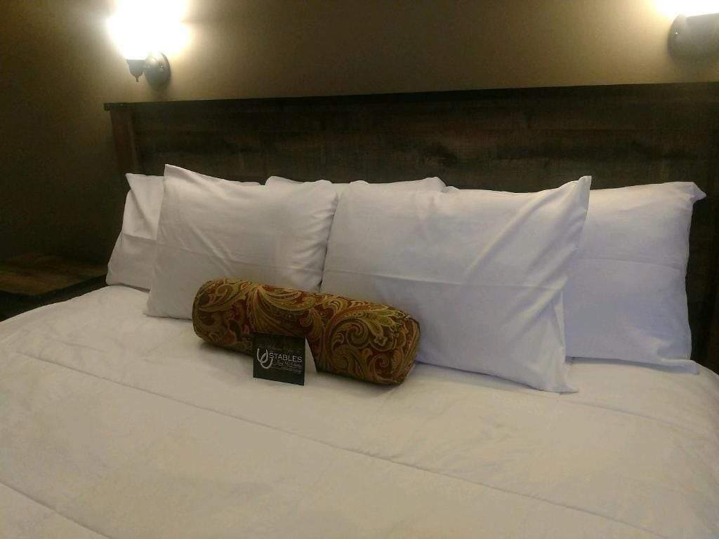 Un llit ben fet amb llençols blancs i una almoinada decorativa.