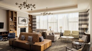 A spacious living room with a large sofa, armchairs, a fireplace, and a chandelier. - Pomeroy Hotel Fort McMurray (Fort McMurray)