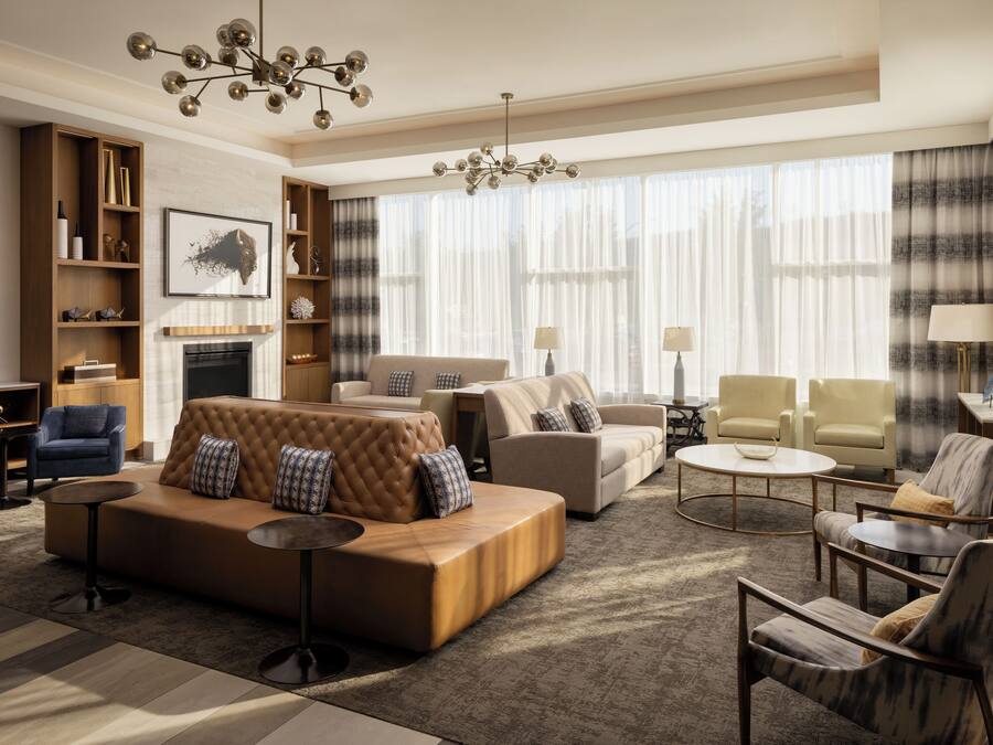 A spacious living room with a large sofa, armchairs, a fireplace, and a chandelier.