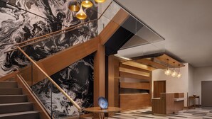 A modern interior with a marble wall, a wooden reception desk, and a checkered floor. - Pomeroy Hotel Fort McMurray (Fort McMurray)