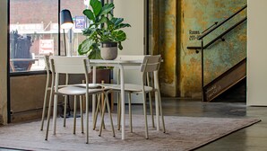 A dining area with a table and four chairs, a potted plant, and a lamp. - Travelers Hotel (Clarksdale)