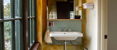 A bathroom with a window, a sink, and a mirror.