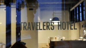 A window with the text "TRAVELERS HOTEL" and a reflection of a bar area with stools and a counter. - Travelers Hotel (Clarksdale)