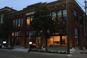 A brick building with large windows and a visible interior space.
