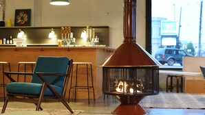 A cozy room with a fireplace, a bar area with bottles and glasses, and a view of the street outside. - Travelers Hotel (Clarksdale)