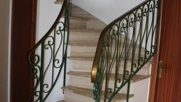 Un escalier en colimaçon avec des rampes en métal ouvragé et des marches en bois.