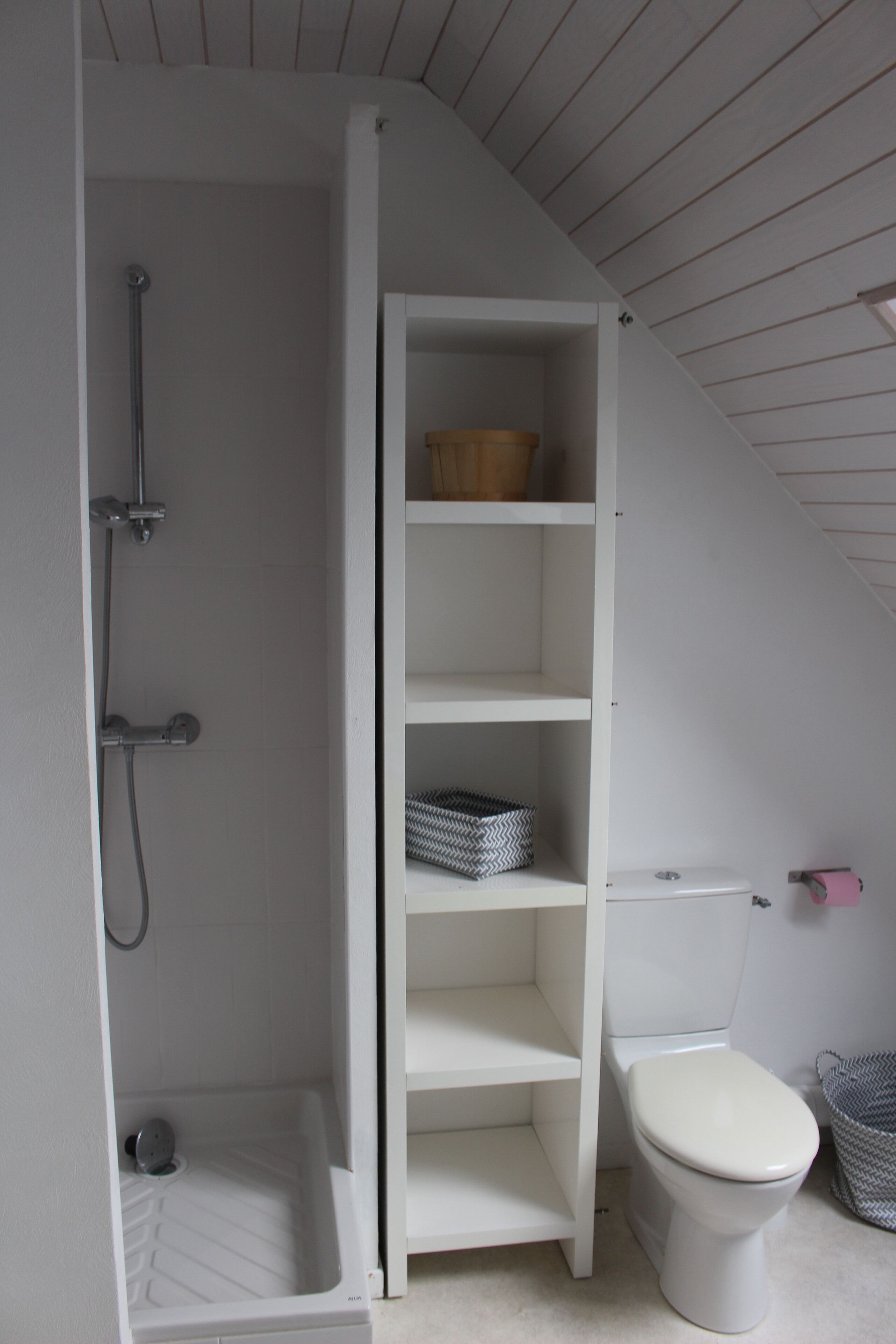 A bathroom with a white bathtub, a toilet, and a built-in shelf unit.