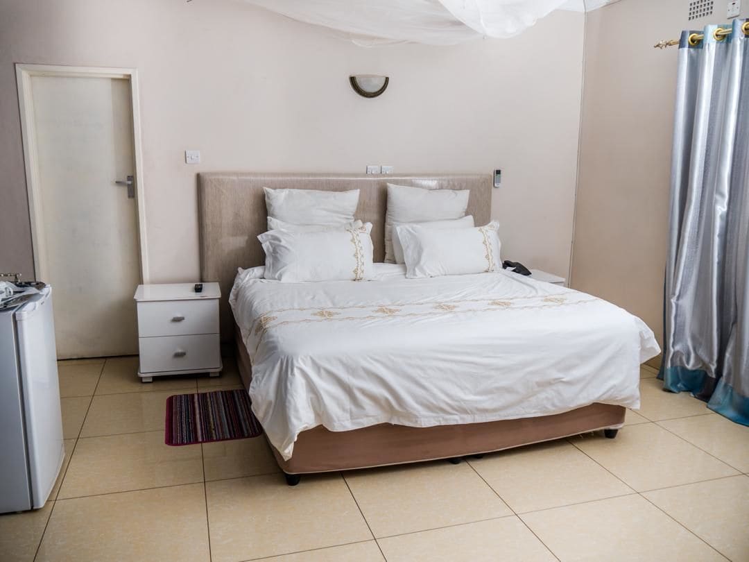 Una habitación de hotel con una cama, una mesita de noche, una pequeña mesa y una cortina.