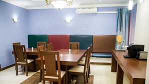 Un comedor con una mesa y sillas de madera, un banco acolchado y un equipo de aire acondicionado en la pared.