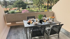 A dining area with a table set for two, chairs, a potted plant, and a bowl of fruit. - Apartment renovated, air conditioning, sea view, swimming pools, tennis (Antibes)