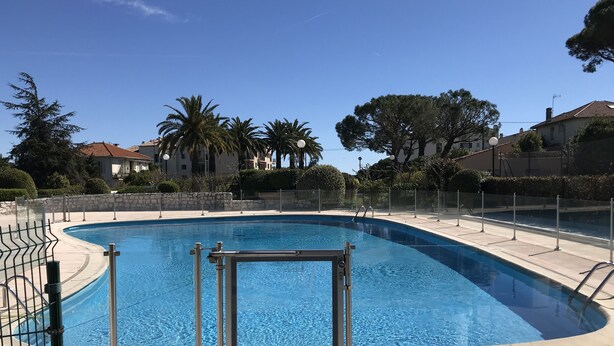A swimming pool with a clear blue water, surrounded by a stone wall and metal railings. - Apartment renovated, air conditioning, sea view, swimming pools, tennis (Antibes)