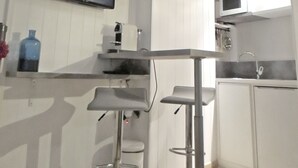 Moderni keittiö, jossa on litteänäyttöinen televisio, valkoiset kaapit, ruostumattomasta teräksestä valmistettu baaritiski ja mikroaaltouuni.